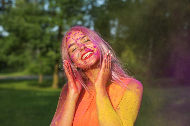Pretty girl having fun with colorful dry paint at the park. Concept for festival Holi. Pretty blonde woman having fun with colorful dry paint at the park royalty free stock photos